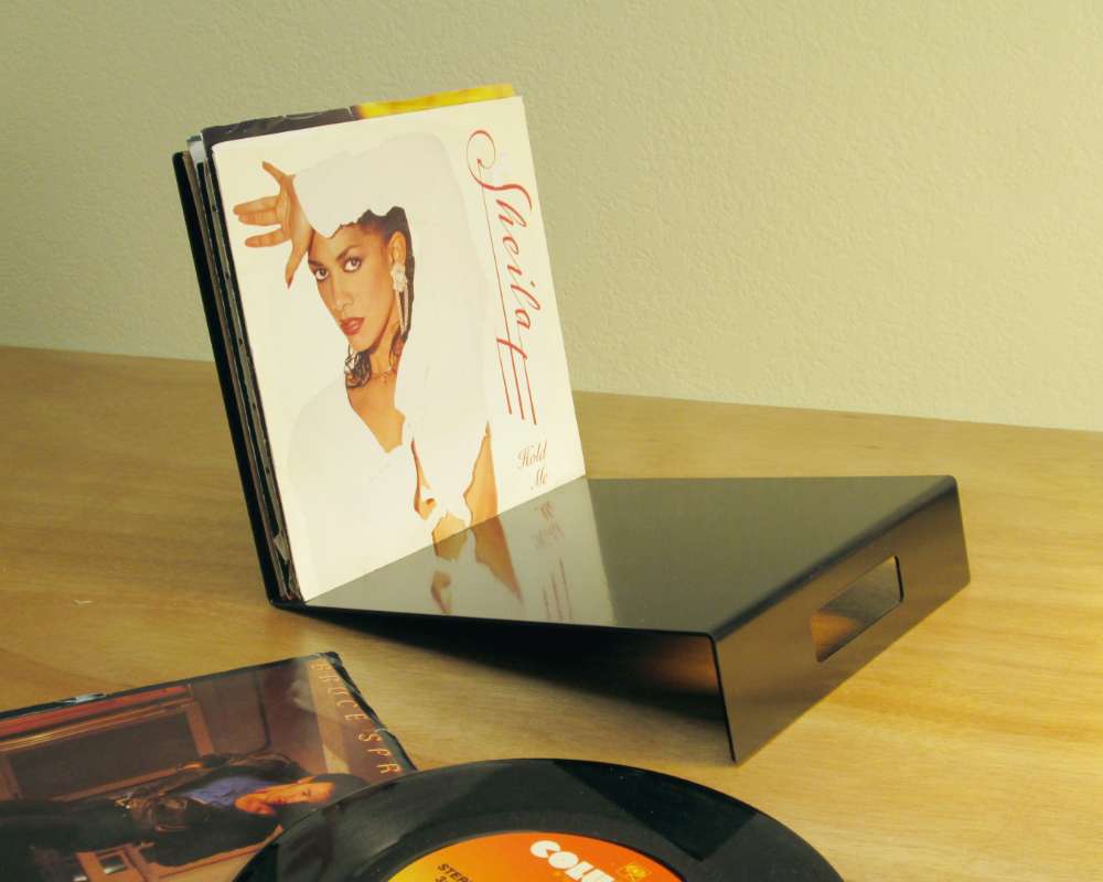 a black metal leaning stand for holding seven inch vinyl records