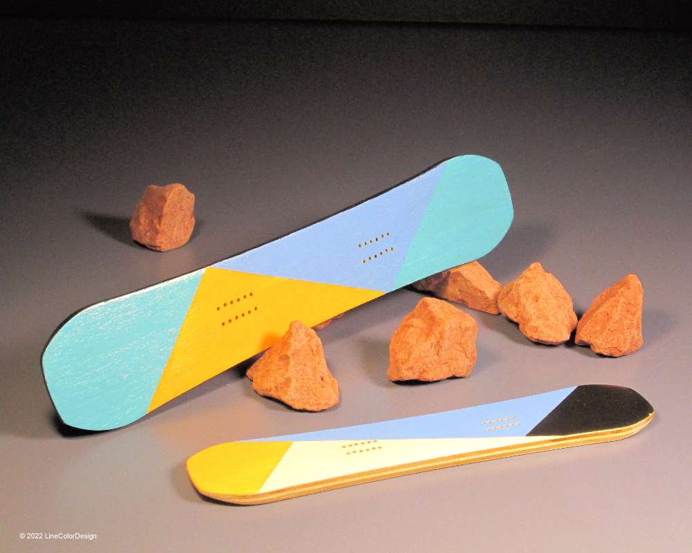 Two miniature wood snowboards leaning against a small rock