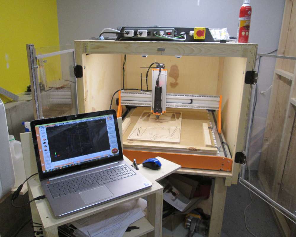 A garage workshop with a CNC machine and a laptop computer.