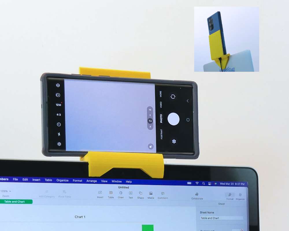 A yellow plastic stand holding a cellphone above a laptop computer screen.