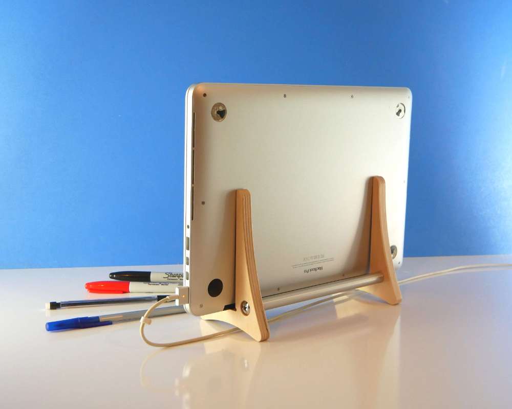 a wood stand holding a closed laptop computer vertically on a table