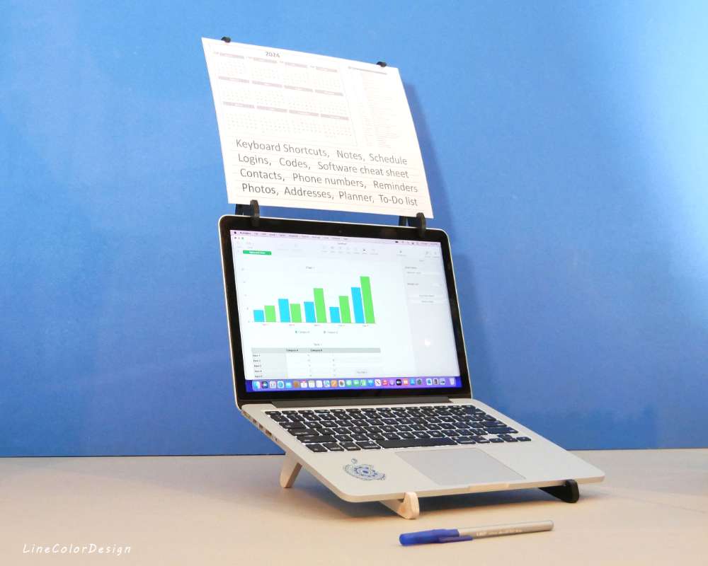 a laptop computer with a paper holder mounted above the screen